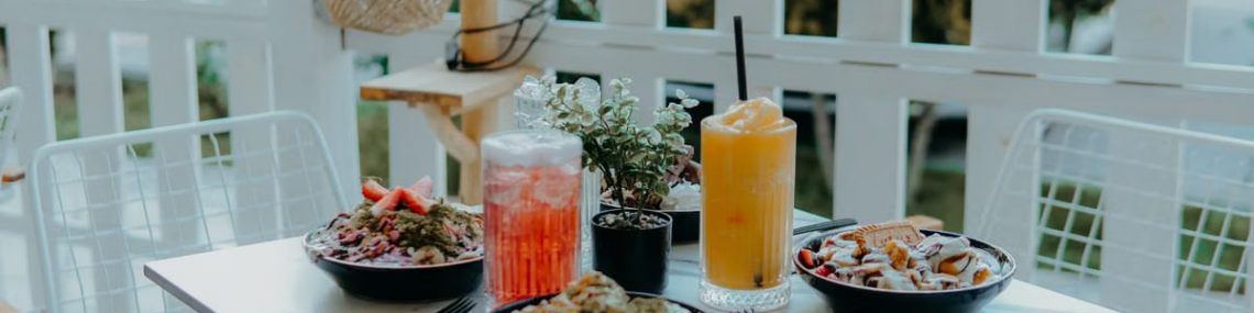 Outdoor dining setup with fresh salads and colorful drinks on a sunny day.